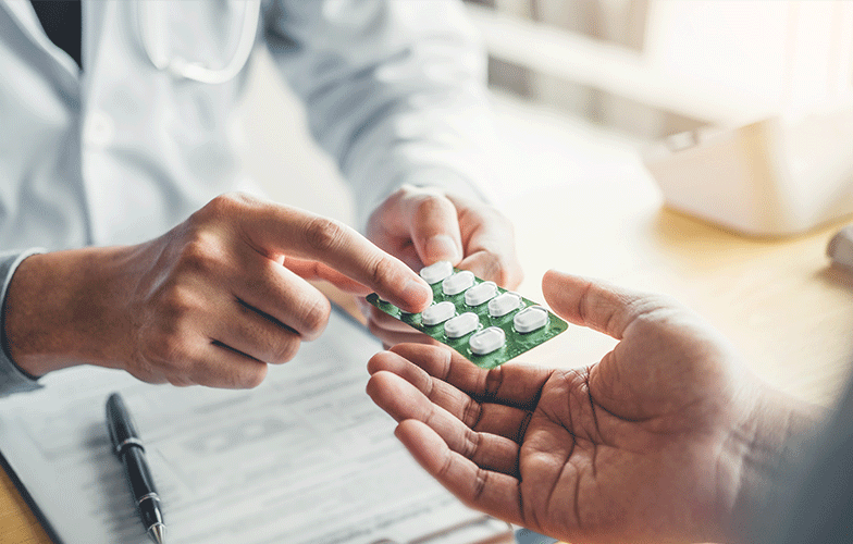 Closeup view of a pharmacist pointing and handing a packet of tablets to a customer